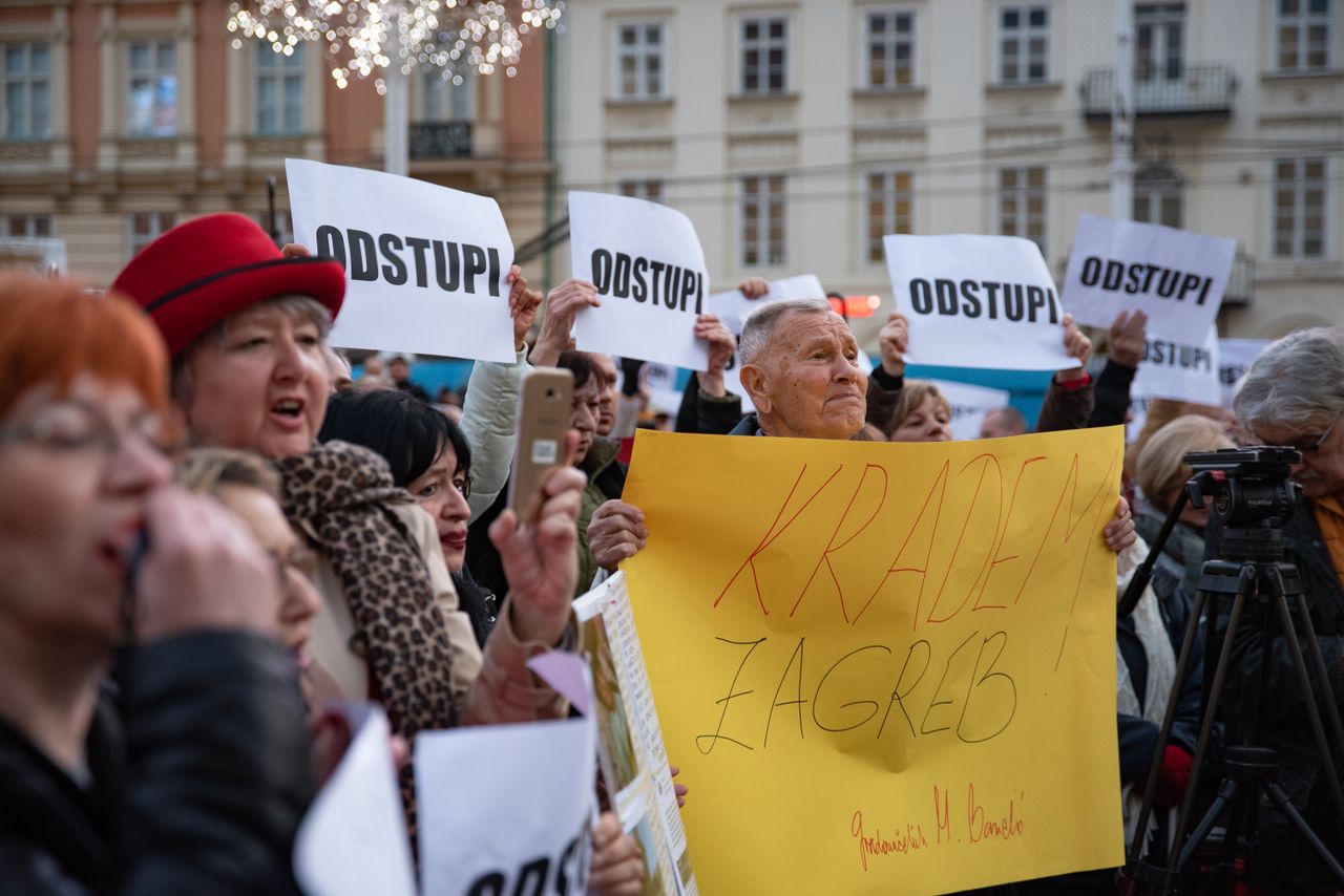 about-img Protesters in Zagreb holding signs demanding resignation during a daytime rally.